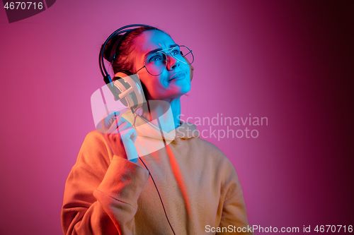 Image of Fashion pretty woman with headphones listening to music over neon background