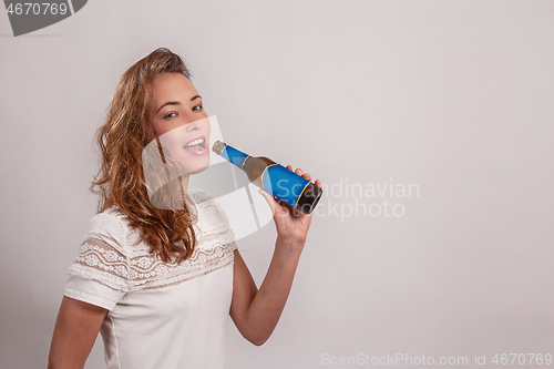 Image of smiling woman drinks from a bottle