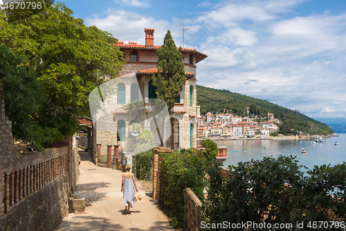 Image of Female tourist walking along Adriatic sea coast relaxing on vacation in Moscenicka Draga, Istria, Croatia.