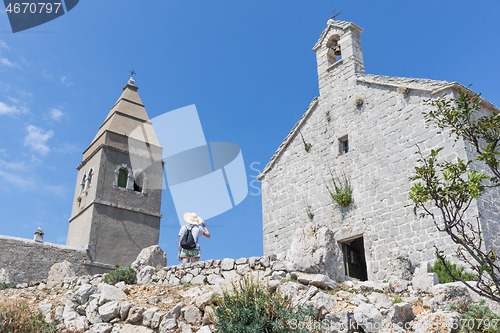 Image of Female traveler sightseeing in an ancient costal village of Lubenice on the island of Cres, Croatia