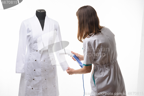 Image of Girl in medical clothes handles steam clothes on manicure