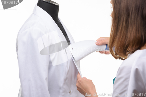 Image of Girl handles medical clothing by steamer on a white background