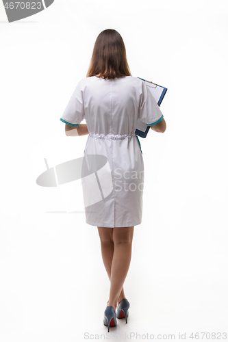 Image of A girl in medical clothing stands back nwa back background