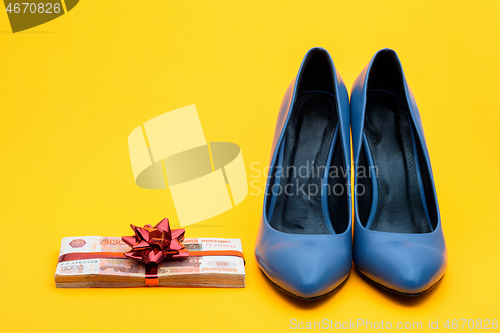 Image of Beautiful women\'s shoes and a wad of money with a gift ribbon on a yellow background