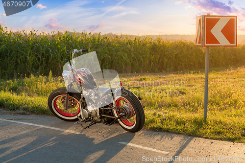 Image of Custom bobber motorbike standing on a road.