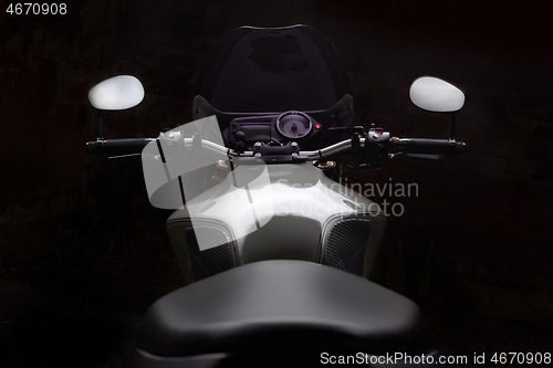 Image of Custom caferacer motorbike on dark background with its headlight on.