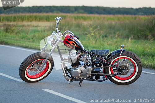 Image of Custom bobber motorbike standing on a road.