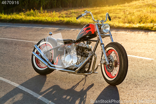 Image of Custom bobber motorbike standing on a road.