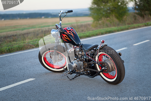 Image of Custom bobber motorbike standing on a road.