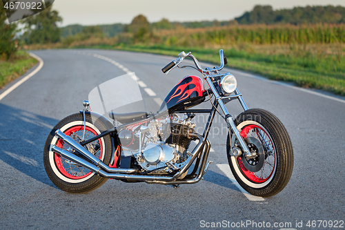 Image of Custom bobber motorbike standing on a road.