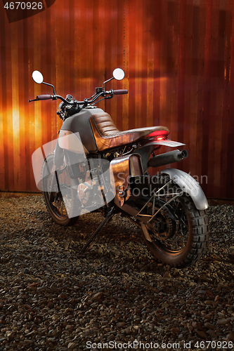 Image of Custom scrambler motorbike on a rusty container background.