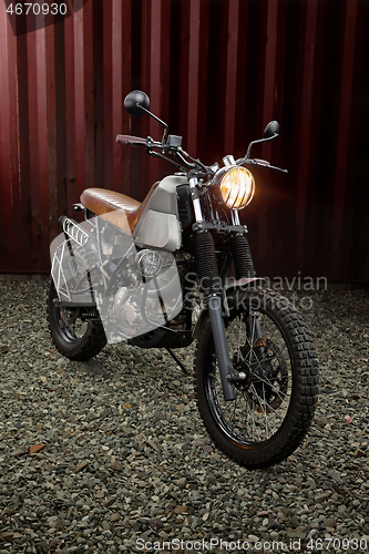 Image of Custom scrambler motorbike on a rusty container background.