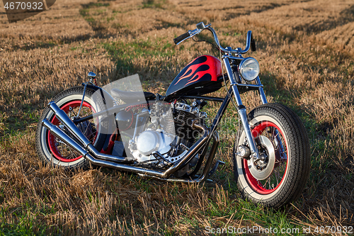 Image of Custom bobber motorbike standing in a wheat field.