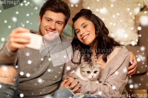 Image of happy couple taking selfie by smartphone at home