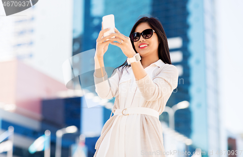 Image of asian woman taking selfie by smartphone in city