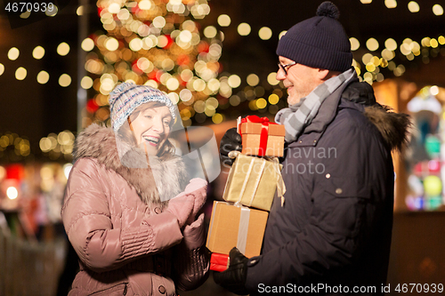 Image of happy senior couple with gift at christmas market