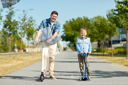 Image of father and little son riding scooters in city