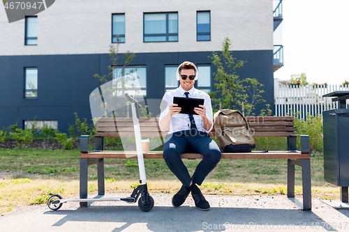 Image of businessman with tablet pc, headphones and scooter
