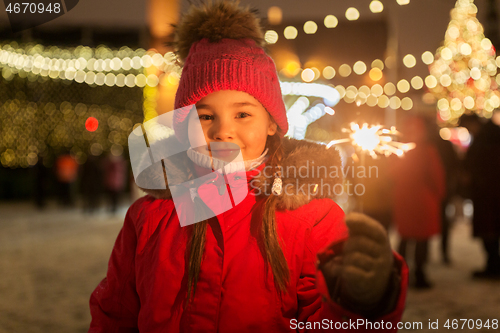 Image of happy girl with sparkler at christmas market