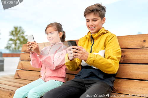 Image of children with smartphones sitting on street bench