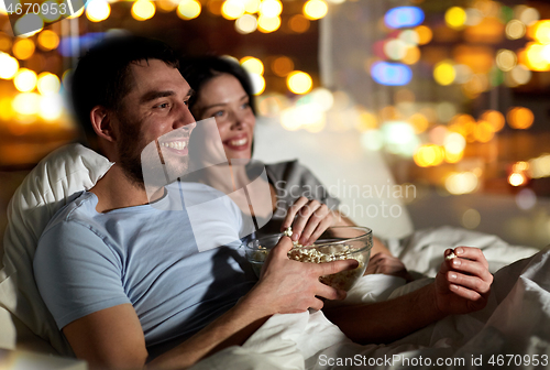 Image of couple with popcorn watching tv at night at home