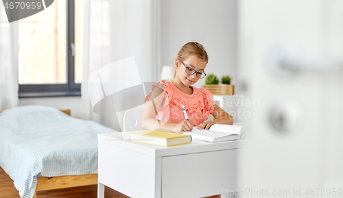 Image of student girl with book writing to notebook at home