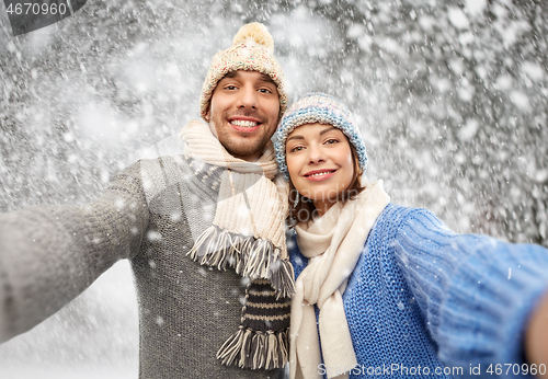 Image of happy couple in winter clothes taking selfie