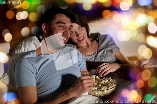 Image of couple with popcorn watching tv at night at home