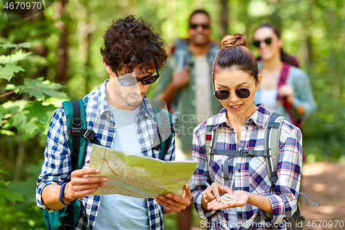 Image of friends with map and backpacks hiking in forest