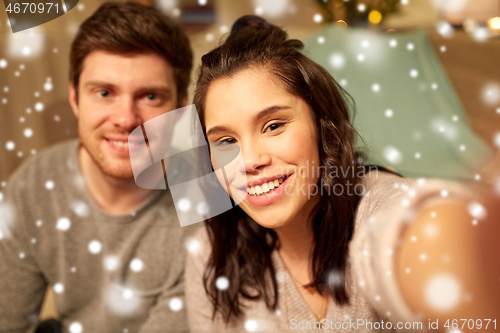 Image of happy couple taking selfie at home