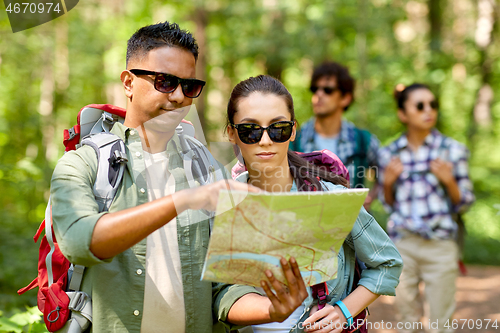 Image of friends with map and backpacks hiking in forest