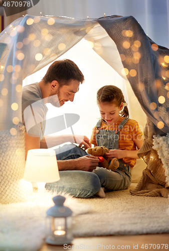 Image of happy family playing with toy in kids tent at home