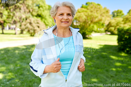 Image of senior woman with earphones running in summer park