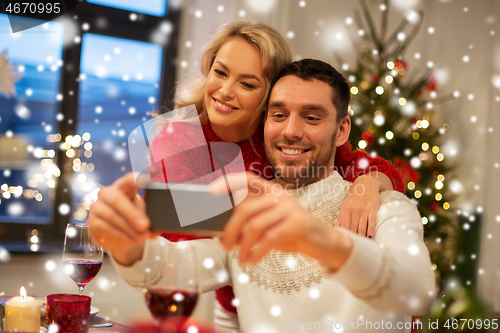 Image of happy couple taking selfie at christmas dinner