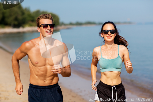 Image of couple in sports clothes running along on beach