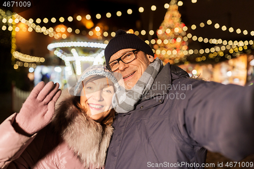 Image of senior couple taking selfie at christmas market