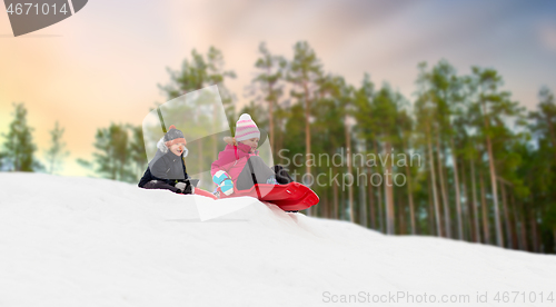 Image of happy kids sliding on sleds down hill in winter