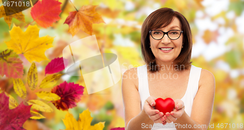 Image of portrait of smiling senior woman holding red heart