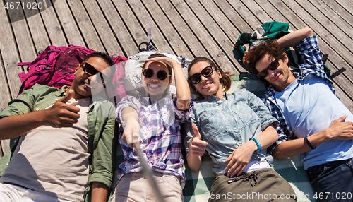 Image of friends or tourists with backpacks taking selfie