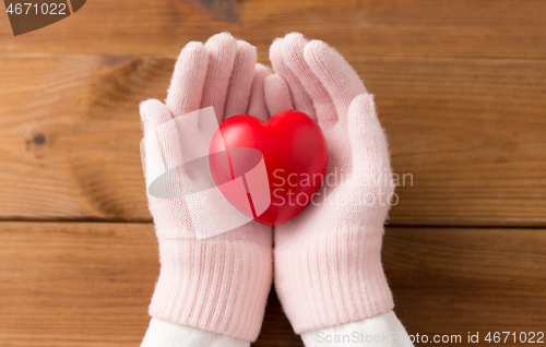 Image of hands in pink woollen gloves holding red heart