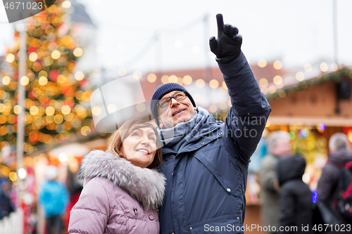 Image of happy senior couple hugging at christmas market