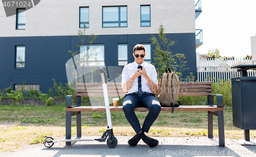 Image of businessman with smartphone, backpack and scooter