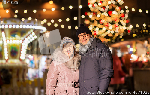 Image of happy senior couple hugging at christmas market