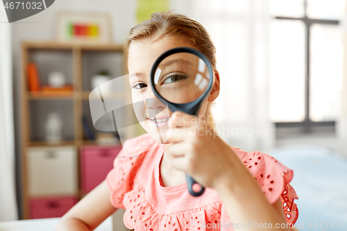 Image of student girl looking through magnifier at home