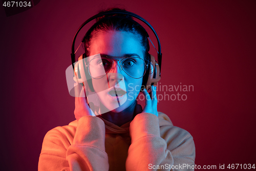 Image of Fashion pretty woman with headphones listening to music over neon background