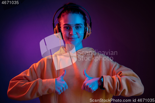 Image of Fashion pretty woman with headphones listening to music over neon background