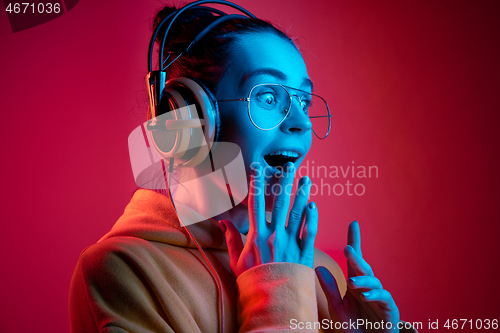 Image of Fashion pretty woman with headphones listening to music over neon background