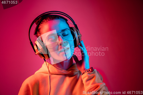 Image of Fashion pretty woman with headphones listening to music over neon background