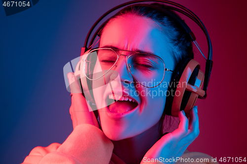 Image of Fashion pretty woman with headphones listening to music over neon background