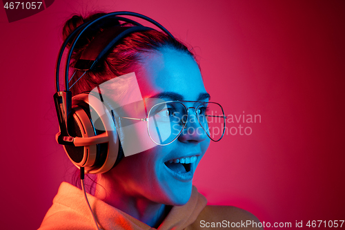 Image of Fashion pretty woman with headphones listening to music over neon background